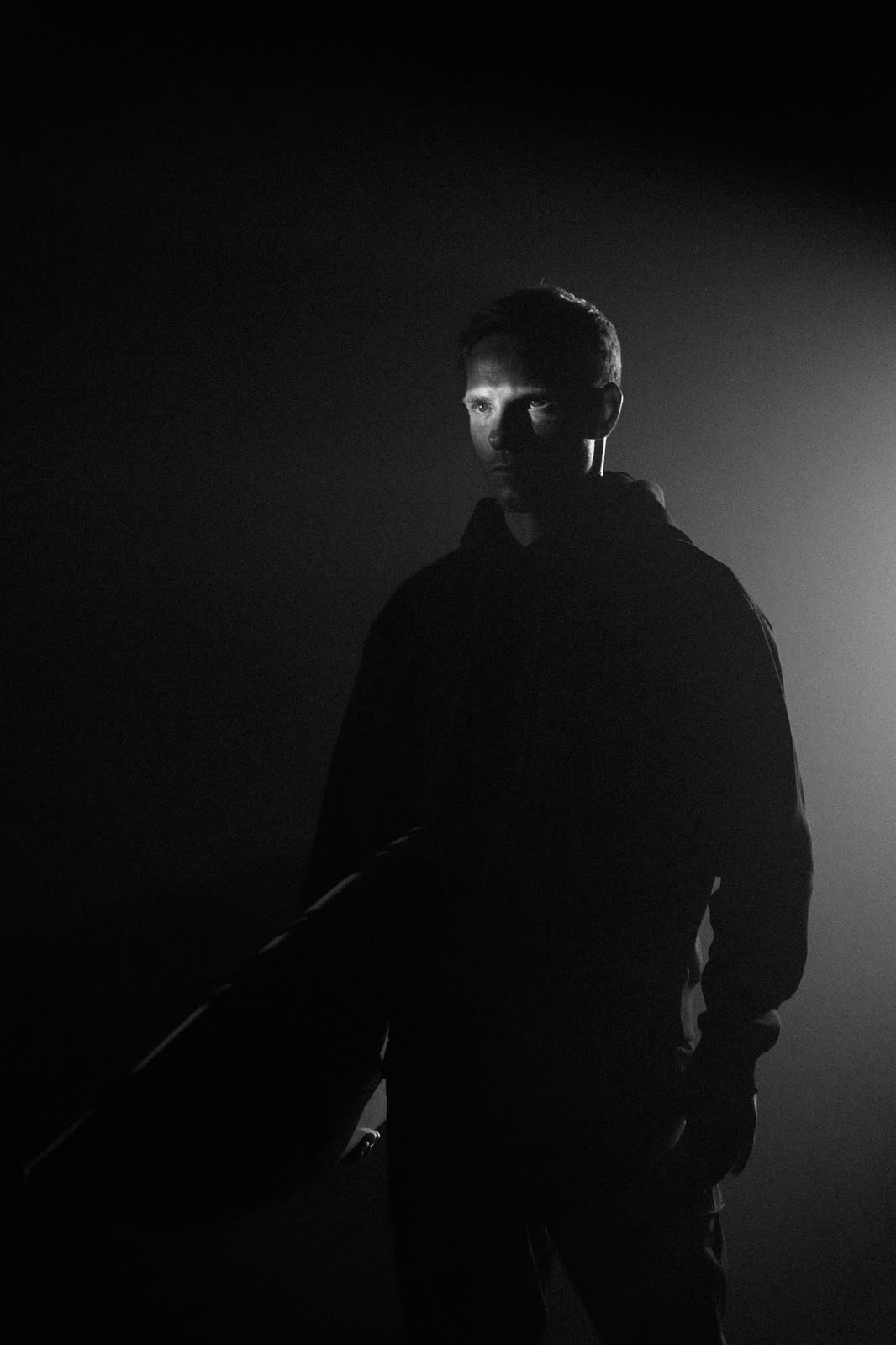 Low-key frame of a figure in shadow carrying a case — Porsche, by Kenneth Kemp